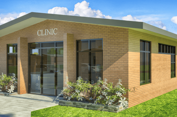 alt=’Exterior view of a brick clinic building with large windows and landscaped flower beds'