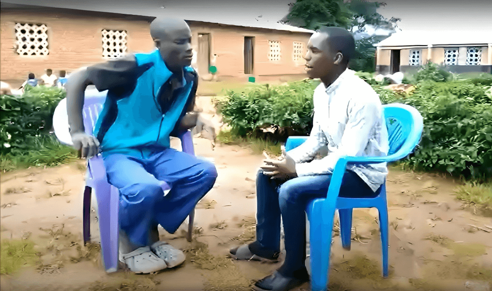 alt=’two parents sitting in blue chairs front of school’